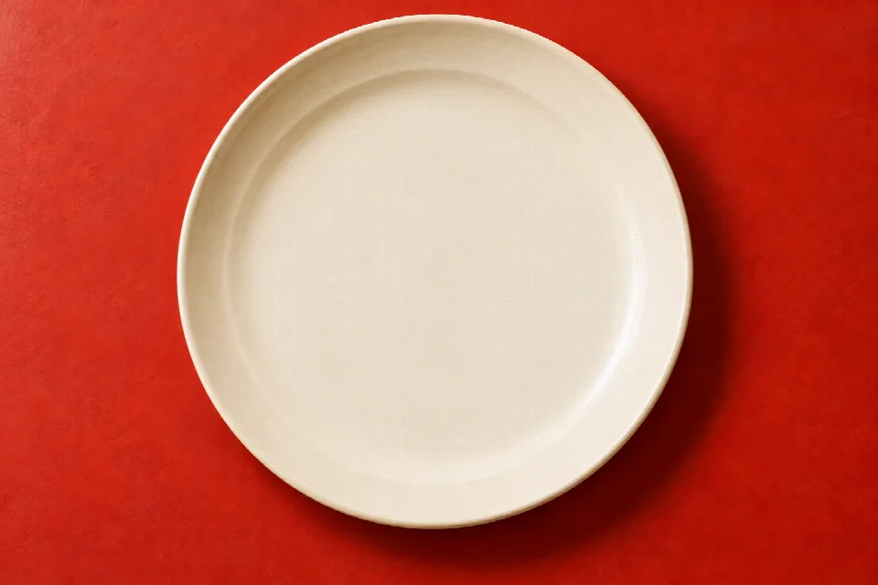 La même assiette crème, vide, sur la même table rouge et dans le même cadrage